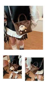 Detailed close-up of dark brown leather tote bag with cream fleece pendant detail