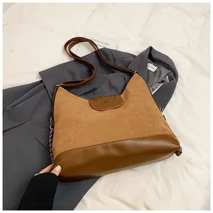 Detail of brown large-capacity tote bag featuring suede textures and embossed flap design