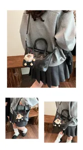 Close-up of retro black leather tote bag with vertical stitching and plush lamb charm