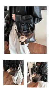 Detail of dark brown leather tote bag with plush lion charm and detachable strap
