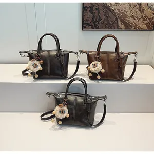 Detailed view of vintage leather tote bags in dark grey and brown with plush charms
