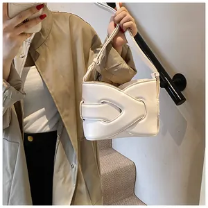 Close-up of minimalist beige crescent underarm bag with layered leather design and strap