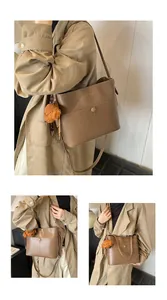 Detailansicht der braunen PU-Leder-Eimertasche mit Zierschnalle und Plüschbär-Anhänger