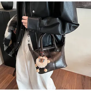 Detail of dark brown tote bag featuring a cute lion plush charm and smooth PU leather
