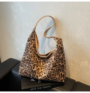 Detail der hobo-tasche mit leopardenmuster und braunem leder-schultergurt
