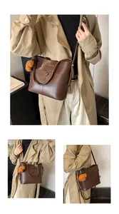 Nahaufnahme der braunen Leder-Eimertasche mit Golddruck und Bären-Plüschanhänger