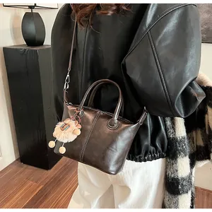 Detail of leather tote bag with contrast stitching and plush lion charm on model