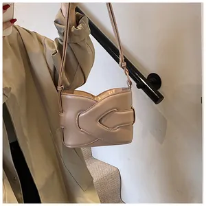 Chic beige crescent underarm bag with pleated design worn by a model on a shoulder