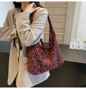 Makro-Detail der Leopardenmuster Hobo-Tasche mit tiefrotem Griff und fester Canvas-Textur