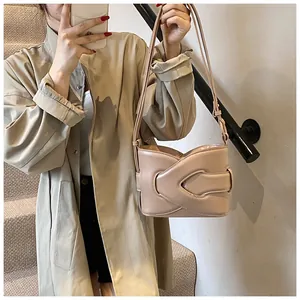 Detail of beige crescent underarm bag with long strap drawstring on a khaki trench coat