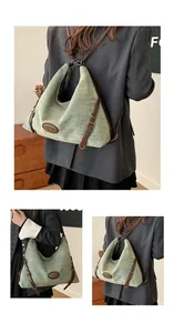 Dettaglio borsa in tela verde chiaro con tracolle regolabili e placca logo in metallo