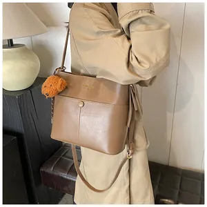 Nahaufnahme der braunen PU-Leder Beuteltasche mit Hundeanhänger und goldener Aufschrift