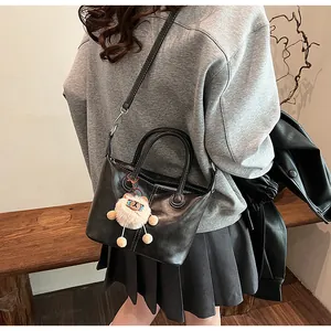 Close-up of black retro tote bag with plush charm accessory worn by model in casual style