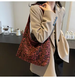 Detailansicht der rotbraunen Hobo-Tasche mit Leopardenmuster, getragen in einem Café