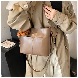 Detail der dunkelbraunen Beuteltasche mit New York Text, Magnetverschluss und Pudelanhänger