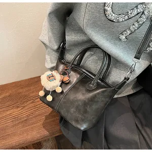 Detail of black matte tote bag featuring dual handles and a cute plush sheep charm