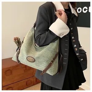 Dettaglio della borsa tote in denim turchese con cinturini in pelle marrone e logo