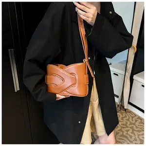 Detail of brown leather crescent bag with layered interlocking design and contrast stitching