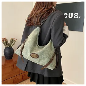 Dettaglio della borsa tote in tessuto verde chiaro con cinturini in pelle marrone e fibbia