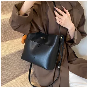 Schicke schwarze Beuteltasche mit Goldschrift an Model in braunem Mantel gezeigt