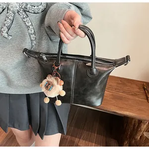 Detail of black trapezoid tote bag with white contrast stitching and plush alpaca charm