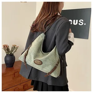 Dettaglio della trama a maglia verde e del cinturino in pelle marrone della borsa a mezzaluna