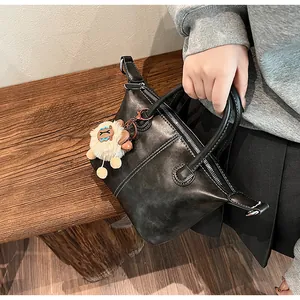 Close-up of black tote bag with white contrast stitching and a cute plush lamb charm