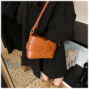 Caramel woven leather underarm bag with a unique overlapping design on model outfit