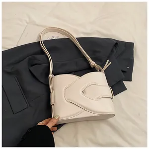 Detail of beige crescent underarm bag showing overlap strap design on blue blazer