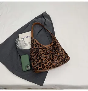 Makroansicht der hobo tasche mit leopardendruck zeigt geräumiges fach mit büchern und handy