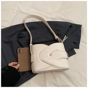 Detail shot of a cream-colored crescent shoulder bag with V-shaped flap and decorative stitching