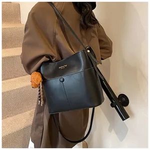Detail der schwarzen Leder-Beuteltasche mit Goldaufschrift und braunem Pelz-Anhänger