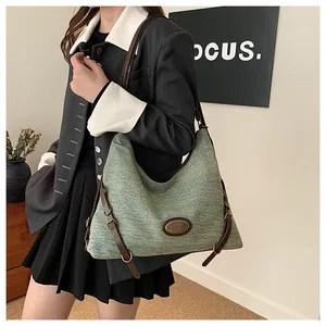 Dettaglio borsa hobo verde scuro con tracolla in pelle marrone indossata da modella