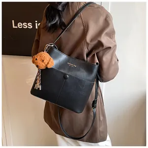 Detail der schwarzen PU-Leder Beuteltasche mit Kontrastnaht und Teddybär-Anhänger
