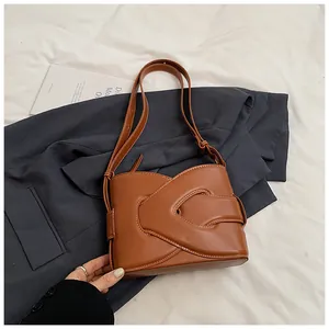 Detail of brown leather crescent bag featuring woven cross-structure and white stitching