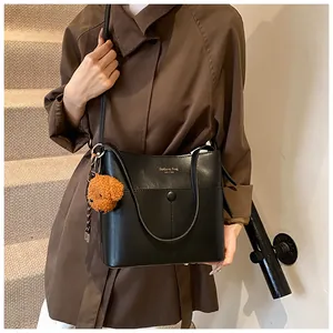 Schicke schwarze Leder-Beuteltasche mit Goldaufdruck und braunem Teddybär-Anhänger Detail