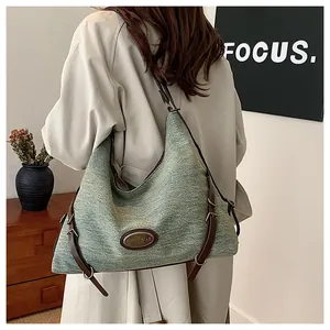 Dettaglio della grande borsa tote in denim grigio-verde con spalline in pelle marrone