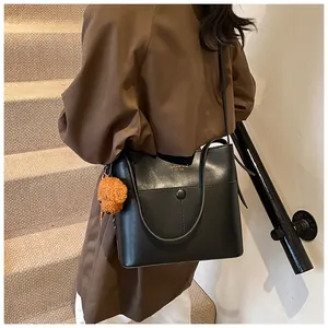 Modische schwarze Lederbeuteltasche mit orangefarbenem Bärenanhänger und Magnetverschluss
