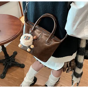 Close-up of brown vintage leather tote bag with a cute white plush sheep keychain