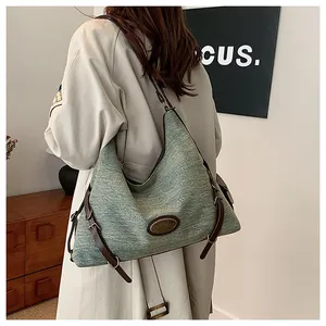 Vista laterale di una grande borsa hobo a mezzaluna in denim indossata da una modella