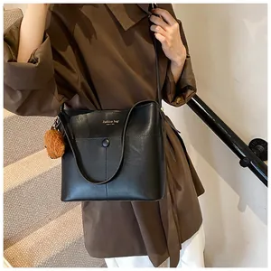 Detail einer schwarzen Leder-Tote-Bag mit braunem Plüsch-Anhänger und Golddruck