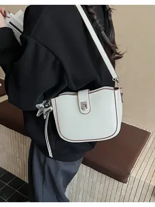 Detail view of cream crossbody bag with brown trim and silver star charm on model