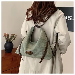 Dettaglio della trama in denim blu e tracolla in pelle marrone su una borsa capiente