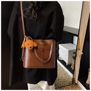 Detail der dunkelbraunen Leder-Eimertasche mit Hundeanhänger und Fashion Bag Aufschrift