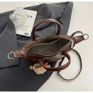 Detail of dark brown leather tote with plush charm and interior storage compartments