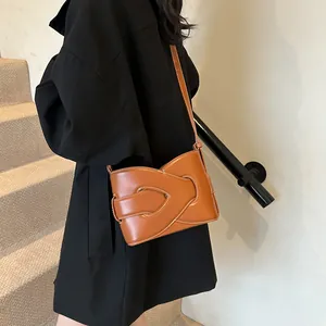 Brown leather crescent underarm bag with white contrast stitching on model