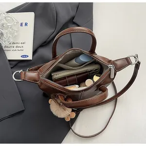 Spacious interior of a brown faux leather tote bag with daily items and plush charm