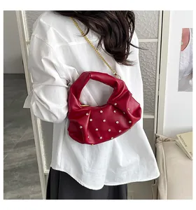 Detail view of dark red pleated handbag with studded rhinestones and golden chain strap