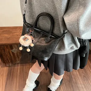 Minimalist black leather tote bag with white stitching and brown sheep charm on model