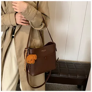 Nahaufnahme der dunkelbraunen Leder-Beuteltasche mit Fashion-Schriftzug und Teddybär